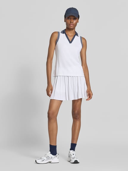 Frauenmodel trägt weißen Minirock mit integrierten Shorts Modell 'Davina' von VARLEY, elastischer Material-Mix, Ganzkörperansicht von vorne.