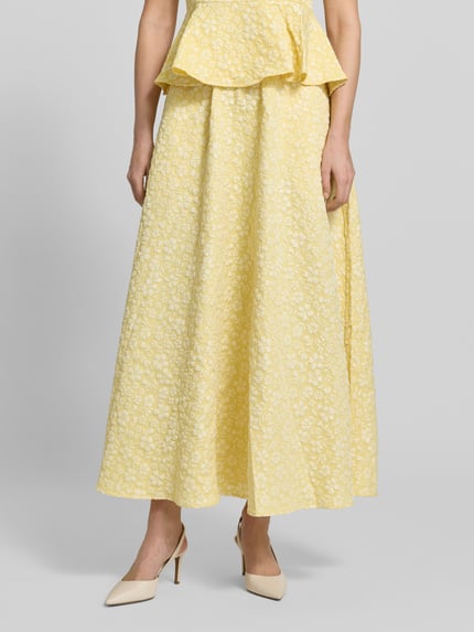 Vrouwenmodel draagt uitlopende maxi-rok met structuurpatroon Modell 'FIONA' van Vero Moda, unikleuring piqué jacquard, regular fit, tailleband elastisch, rechte zoom, zijzakken. Close-up onderlichaam vooraanzicht.