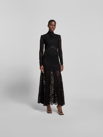 Modelka nosi Maxikleid aus Spitze mit Stretch-Anteil od Rabanne, czarna koronka, elastyczny materiał, krój slim fit, długość całkowita 149 cm, szerokość w rozmiarze S/M: 40 cm, długość rękawa 68 cm, szerokość talii 31 cm, długi rękaw, stójka, widok całej sylwetki z przodu.