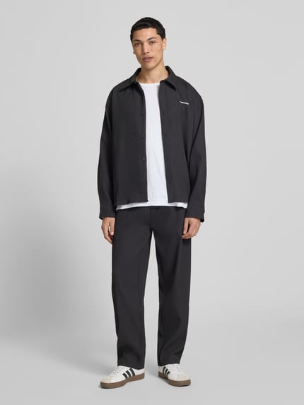 Männermodel trägt Regular Fit Freizeithemd mit Kentkragen und Label-Stitching von Pegador, Schwarz, Material-Mix mit Stretch-Anteil, Ganzkörperansicht von vorne. Rückenlänge bei Größe M: 68 cm, Schulterbreite: 50 cm, Ärmellänge: 60 cm, Modell 'Troy'.