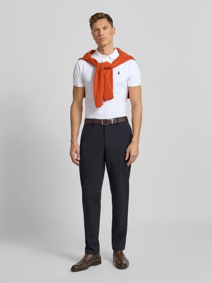 Männermodel trägt Poloshirt mit Label-Stitching von Polo Ralph Lauren, Reine Baumwolle, Slim Fit, Ganzkörperansicht von vorne.