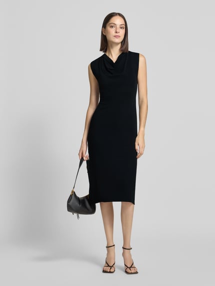 Frauenmodel trägt schwarzes Strickkleid mit Wasserfall-Ausschnitt, gerader Schnitt, Midilänge, Strickkleid mit Wasserfall-Ausschnitt Modell 'SANTA' von MANGO, Ganzkörperansicht von vorne.