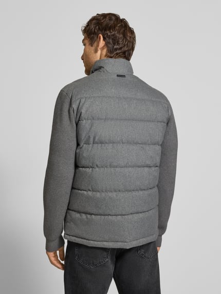 Männermodel trägt Steppjacke mit Stehkragen und Zweiwege-Reißverschluss von Christian Berg Men in Grau, Regular Fit, Ganzkörperansicht Rückansicht. Kontext: Reißverschlusstaschen, Rückenlänge 70 cm, Schulterbreite 51 cm, Brustweite 60 cm, Ärmellänge 69 cm.
