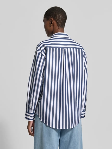 Frauenmodel trägt Relaxed Fit Langarmbluse aus reiner Baumwolle von GANT, gestreift in Blau und Weiß, leichte Textur, Ganzkörperansicht Rückansicht.