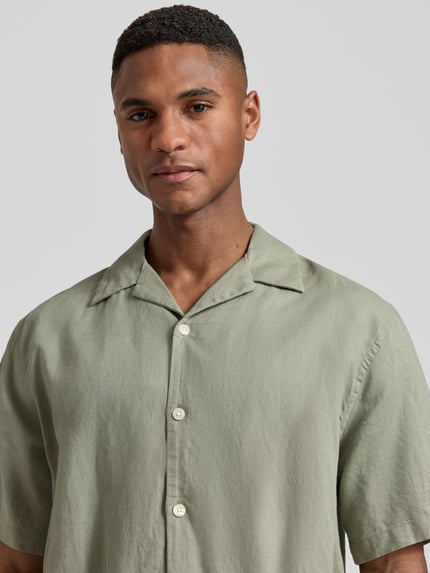 Männermodel trägt Relaxed Fit Freizeithemd aus Leinen-Baumwoll-Mix Modell 'RLXCLAY' von HUGO in Hellgrün, Nahaufnahme Oberkörper.