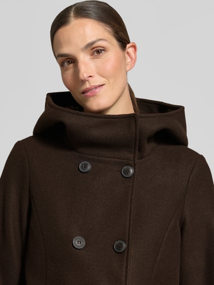 Vrouwenmodel draagt Wollmantel mit Kapuze van VERO MODA, effen bruin, dubbele knoopsluiting, kapkraag, zijzakken, lange mouw, afgeronde zoom, close-up bovenlichaam