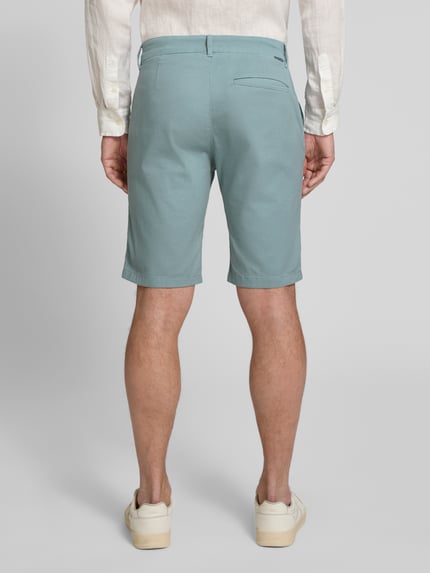 Männermodel trägt Slim Fit Chinoshorts aus reiner Baumwolle von Tom Tailor, Optik: Unifarben, Paspeltaschen, Ganzkörperansicht Rückansicht.