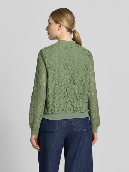 Vrouwenmodel draagt Regular Fit blouson uit mix van katoen van Vero Moda, all-over bloemenmotief, gehaakt, groene tinten, lange mouw, rompzoom geribd, model 'HONEY'. Ganzkörperansicht Rückansicht.