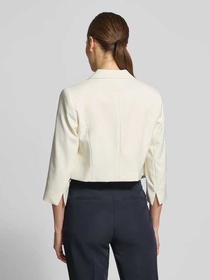 Frauenmodel trägt Cropped Blazer mit Reverskragen von Betty Barclay in Creme, 3/4-Arm, elastischer Mix, Rückansicht, Ganzkörperansicht.