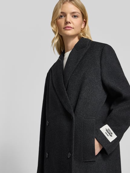Frauenmodel trägt Oversized Mantel aus Woll-Mix von Karo Kauer in dunkler Farbe mit Reverskragen und Knopfverschluss, Nahaufnahme Oberkörper.