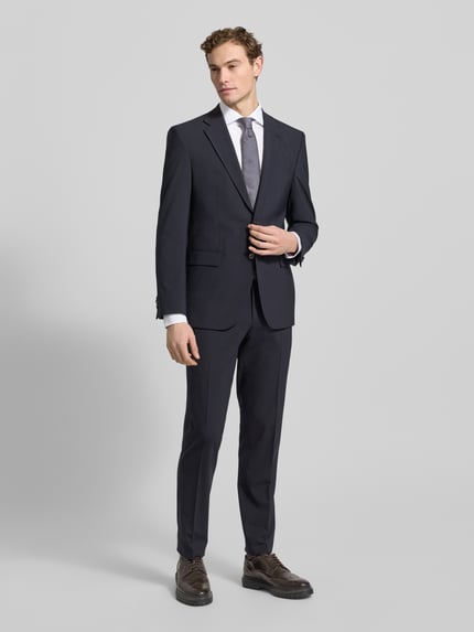 Männermodel trägt Super Slim Fit Businesshemd aus Baumwoll-Mix von Jake*s, dunkle Farbe, glatte Textur, Ganzkörperansicht von vorne. Rückenlänge 79 cm, Schulterbreite 45 cm, Ärmellänge 67 cm, Haikragen, Knopfleiste, Stretch-Anteil.