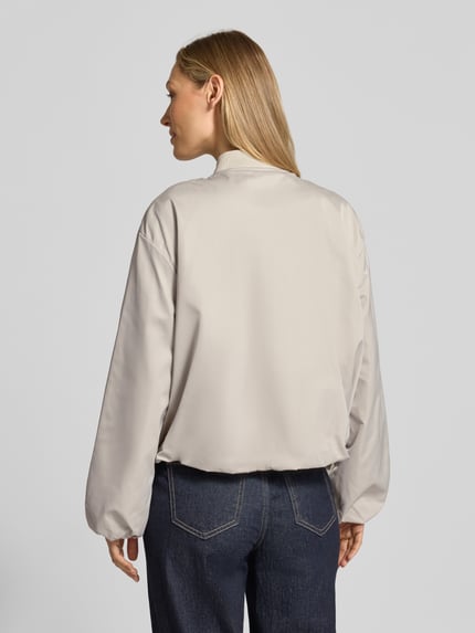 Modelka kobieca ma na sobie Regular Fit Blouson mit Baseball-Kragen od Marc O'Polo, efekt: jednolity kolor, bufiaste rękawy, wpuszczane kieszenie, materiał z recyklingu, zamek błyskawiczny, krój regular fit, kształt kołnierza: baseball, wykończenie: elastyczny tunel, Ganzkörperansicht Rückansicht.