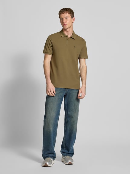 Männermodel trägt Straight Fit Poloshirt mit Label-Stitching von Calvin Klein Jeans aus reiner Baumwolle, Polokragen, gerippte Ärmelabschlüsse, olivgrün, Rückenlänge 71 cm bei Größe M, Ganzkörperansicht von vorne.