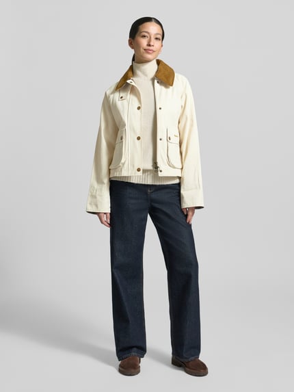 Frauenmodel trägt Regular Fit Parka aus reiner Baumwolle von Barbour in Unifarben mit Umlegekragen und Pattentaschen, Ganzkörperansicht von vorne.