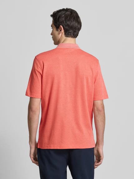 Männermodel trägt Regular Fit Poloshirt mit Brusttasche von Christian Berg Men in Koralle, Baumwoll-Mix, Ganzkörperansicht Rückansicht.