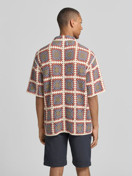 Mężczyzna nosi Loose Fit Freizeithemd mit Kentkragen von JAKE*S STUDIO MEN z mieszanki bawełny, imitacja wykonania na szydełku, listwa guzikowa, długość tyłu w rozmiarze M: 75 cm, szerokość ramion w rozmiarze M: 63 cm, długość rękawów w rozmiarze M: 27 cm, kolorowy wzór geometryczny, widok całej sylwetki z tyłu.