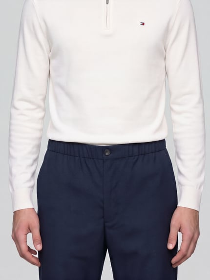 Männermodel trägt Low Waist Stoffhose mit Logo-Detail von Tommy Hilfiger in Dunkelblau, feines Web­mus­ter, Wollmix, Nahaufnahme Oberkörper.