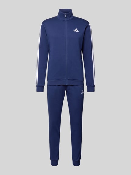 Produktfoto, 'Trainingsanzug mit Label-Details' von adidas Sportswear in Blau mit weißen Streifen, prosty krój, stójka, zamek błyskawiczny, elastyczne wykończenia, wpuszczane kieszenie, elastyczny pas, szerokość w rozmiarze M: 38 cm, długość tyłu: 70 cm, szerokość ramion: 46 cm, długość rękawów: 63 cm, długość wewnętrzna nogawki: 78 cm