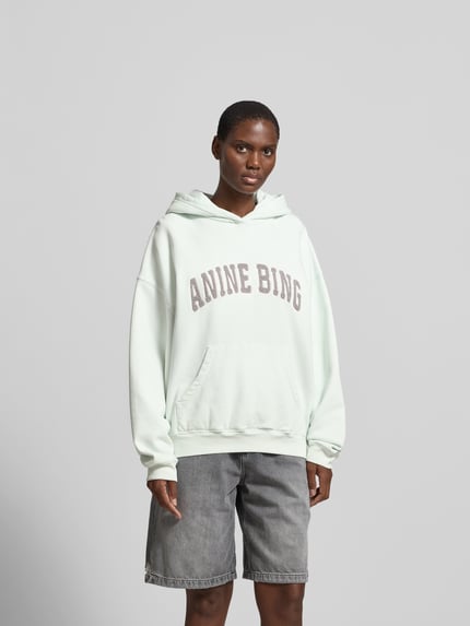 Vrouwenmodel draagt Oversized Hoodie met Logo-Stitching van Anine Bing in lichtgroen, pure katoen, oversized fit, capuchon, kangoeroezak, ruglengte maat S 64 cm, vooraanzicht van het volledige lichaam