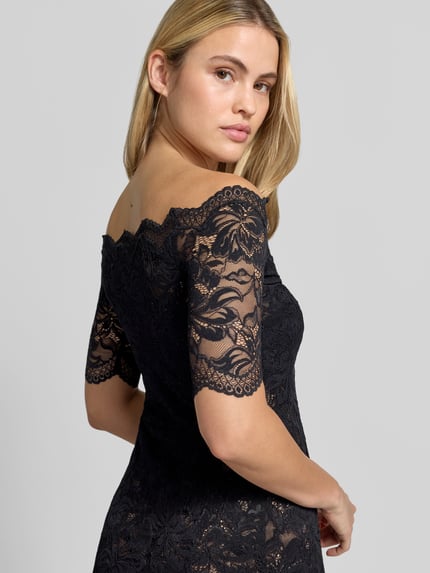 Frauenmodel trägt Abendkleid mit Spitzenbesatz von Rabanne in Schwarz mit floralem Spitzenmuster und Muschelsaum, Nahaufnahme Oberkörper.