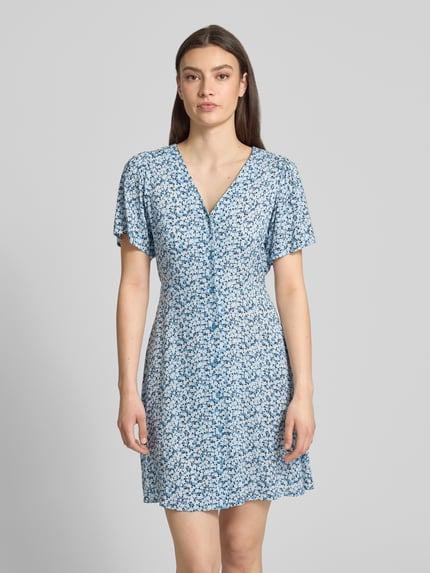 Frauenmodel trägt Minikleid aus reiner Viskose Modell 'EVIDA' von Only mit Allover-Muster, tailliert, V-Ausschnitt, Kurzarm, Knopfleiste, Gürtel, Ganzkörperansicht von vorne.