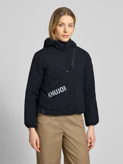 Frauenmodel trägt schwarze khujo Damen Jacke mit Kapuze und Label-Detail Modell 'SHELLY2', Regular-Fit, Reißverschluss, Nahaufnahme Oberkörper. Rückenlänge bei Größe S: 56 cm, Schulterbreite: 52 cm, Brustweite: 46 cm, Ärmellänge: 52 cm.