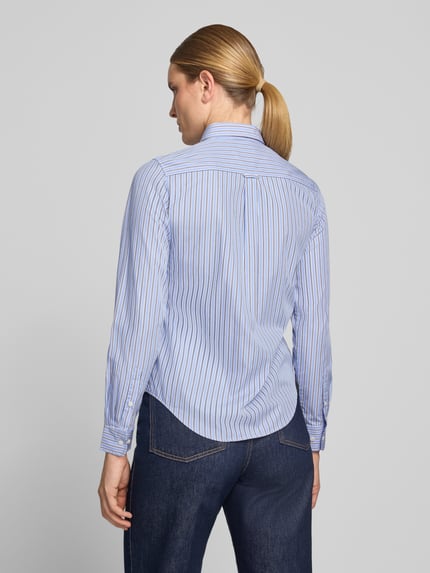 Frauenmodel trägt Regular Fit Langarmbluse aus reiner Baumwolle von GANT in Hellblau mit feinen Streifen, Ganzkörperansicht Rückansicht.