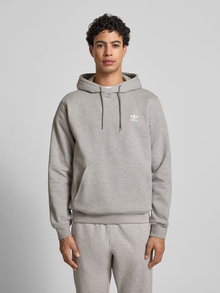 Männermodel trägt Hoodie mit Kapuze von adidas Originals aus Baumwoll-Mix, Lockerer-Schnitt, Känguru-Tasche, Label-Stitching, Ganzkörperansicht von vorne.