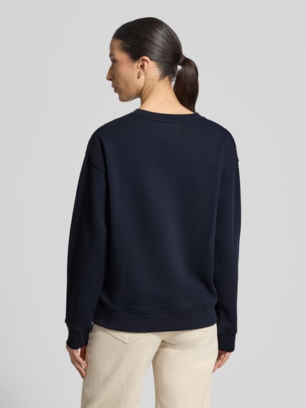 Frauenmodel trägt Sweatshirt mit Label-Stitching und Rundhalsausschnitt von Gant aus reiner Baumwolle, krój loose fit, rippenbündchen, Ganzkörperansicht Rückansicht