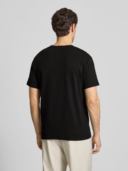 Männermodel trägt Regular Fit T-Shirt aus Baumwoll-Mix Modell 'SPENCER' von SELECTED HOMME in Schwarz, gestreift strukturiert, Ganzkörperansicht Rückansicht.