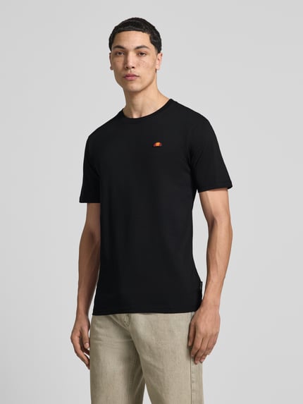 Männermodel trägt T-Shirt mit Label-Stitching Modell 'CASSICA' von Ellesse in Schwarz aus Reine Baumwolle, Gerader-Schnitt, Nahaufnahme Oberkörper.