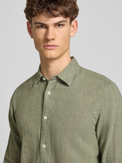 Männermodel trägt Slim Fit Freizeithemd aus Baumwoll-Leinen-Mix Modell 'CAIDENLS SOLID' von Only & Sons in Grün, Optik: Unifarben, Flammgarn-Struktur, Nahaufnahme Oberkörper.