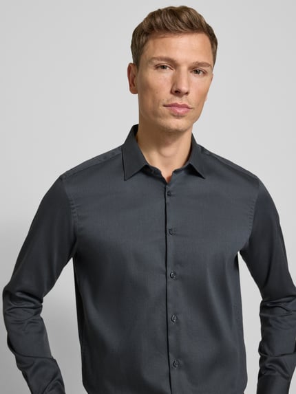 Männermodel trägt Regular Fit Business Hemd aus Baumwolle mit Kentkragen von Jake*s, glatte Textur in Dunkelgrau, Nahaufnahme Oberkörper.