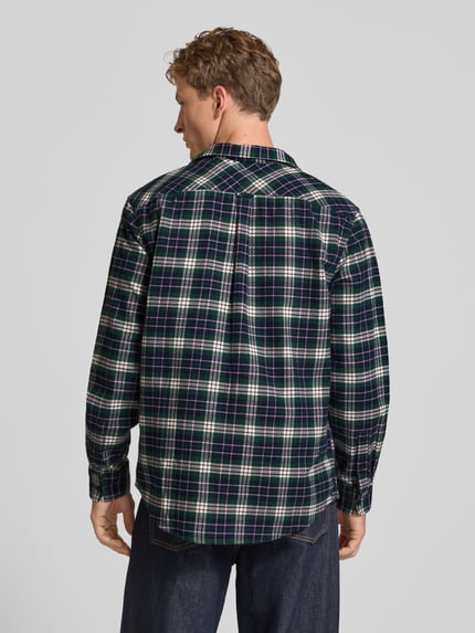 Männermodel trägt Relaxed Fit Freizeithemd aus reiner Baumwolle von Tommy Jeans, kariertes Muster in Dunkelblau und Grün, Ganzkörperansicht Rückansicht. Herren Freizeithemd von Tommy Jeans.