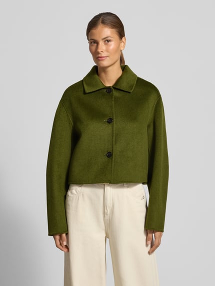 Frauenmodel trägt Jacke aus Lanawoll-Mix mit Knopfleiste Modell 'ALEX' von MANGO in Olivgrün, glatte Textur, Ganzkörperansicht von vorne. Regular Fit, Umlegekragen, Viskose-Anteil, bei Größe S: Rückenlänge 51 cm, Schulterbreite 39 cm, Brustweite 42 cm, Ärmellänge 58 cm.