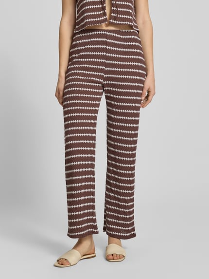 Vrouwenmodel draagt Loose Fit Stoffhose met Baumwoll-Anteil Modell 'EVA LIFE' van Only, bruin-wit allover patroon, flared, strickstructuur, elastische taille, materiaal-mix met katoen, volledige vooraanzicht.