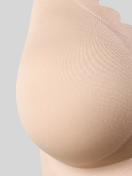 Vrouwenmodel draagt Unterhemd mit Wellensaum und herausnehmbaren Pads van Skiny in lichtbeige, materiaalmix met stretch, golvende zoom, nauwsluitend, uitneembare pads, verstelbare bandjes, detailopname bustgedeelte