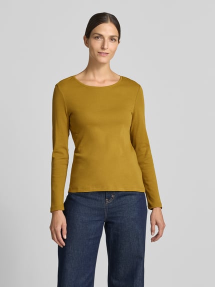 Frauenmodel trägt Slim Fit Longsleeve aus reiner Baumwolle von Christian Berg Woman in Senfgelb mit Rundhalsausschnitt, Ganzkörperansicht von vorne.