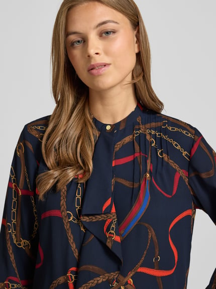 Kobiece model prezentuje bluzkę Regular Fit Bluse mit Volants Modell 'JASLIE' od Lauren Ralph Lauren, wzór na całej powierzchni, okrągły dekolt, zapięcie na guzik, falbany, długość tyłu 66 cm, długość rękawów 59 cm, ujęcie: zbliżenie górnej części ciała