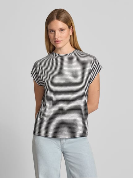 Frauenmodel trägt Loose Fit T-Shirt aus reiner Baumwolle von Armedangels, gestreift, schwarz-weiß, ohne Ärmel, Ganzkörperansicht von vorne.