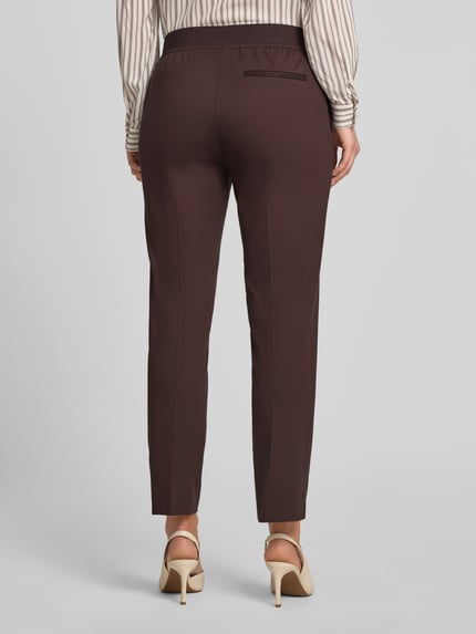Frauenmodel trägt Regular Fit Marlenehose aus Viskose-Mix Modell 'TAPRIA-CROP' von BOSS in Optik: Unifarben mit Label-Applikation, seitlichen Eingrifftaschen, Gesäßtaschen, Stretch-Materialverarbeitung, Bundabschluss: elastisch, Ganzkörperansicht Rückansicht.