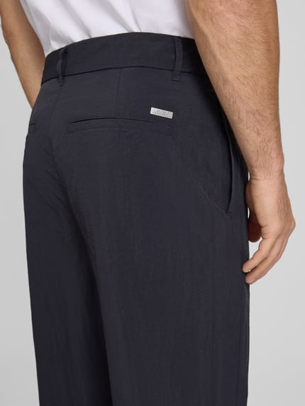 Męski model nosi Hose mit Gesäßtaschen und Label-Detail von ARMANI EXCHANGE, krój regular fit, czarne, tekstura gładka, detal z logo, tylne kieszenie, szerokość w rozmiarze 32: 44 cm, długość nogawki od wewnątrz 79 cm, detailaufnahme tylnej części.