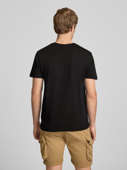 Männermodel trägt T-Shirt mit Logo und Rundhalsausschnitt von Alpha Industries aus Reiner Baumwolle im Regular-Fit, schwarze Farbe, Rückenlänge bei Größe M 67 cm, Ganzkörperansicht Rückansicht.