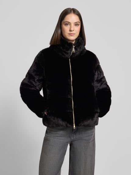 Frauenmodel trägt schwarze, glänzende Webpelzjacke mit Zweiwege Reißverschluss von S. OLIVER BLACK LABEL, unifarben, Struktur-Optik, Regular Fit, metallische Akzente, Kragen, seitliche Eingrifftaschen, cropped Länge, Fleece-Material, Ganzkörperansicht von vorne.