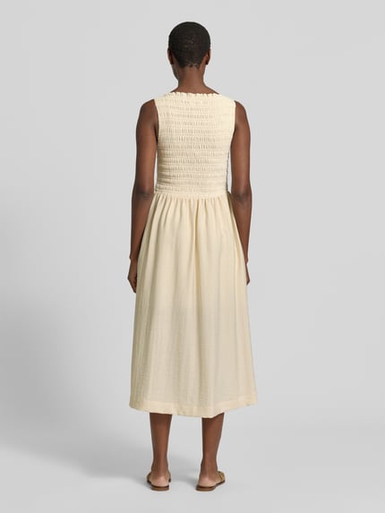 Frauenmodel trägt Midikleid mit Smok-Details von Jake*s Casual in Creme, Material-Mix mit Stretch-Anteil, A-Linie, Rückenlänge 122 cm, Brustweite 32 cm, Ganzkörperansicht Rückansicht.