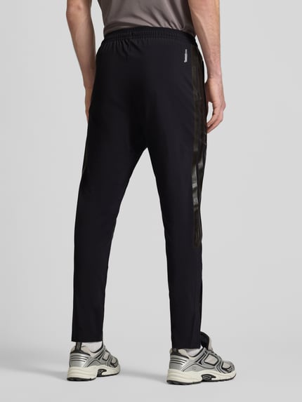 Männermodel trägt Spodnie dresowe mit elastycznym pasem von adidas Sportswear, mieszanka materiałów z dodatkiem streczu, luźny krój, tunel, wpuszczane kieszenie, długość wewnętrzna nogawki w rozmiarze M: 71 cm, widok całej sylwetki z tyłu.