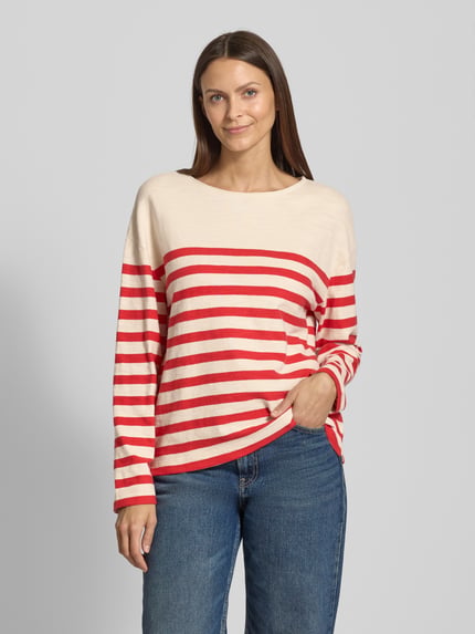 Frauenmodel trägt Regular Fit Strickpullover aus reiner Baumwolle von Marc O'Polo, Optik: Allover-Muster, Feinstrick, Rundhals, Langarm, geschlitzter Rumpfabschluss, Farbe Creme mit roten Streifen, Ganzkörperansicht von vorne.