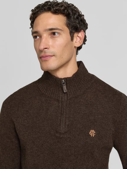Männermodel trägt Regular Fit Strickpullover aus reiner Wolle von MCNEAL in Braun, Logo-Stickerei, gerippte Bündchen, Nahaufnahme Oberkörper.