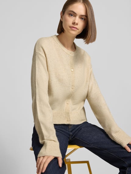 Frauenmodel trägt Cardigan mit Woll-Anteil Modell 'NATALIE' von JJXX in Beige mit Strick-Optik, Nahaufnahme Oberkörper.