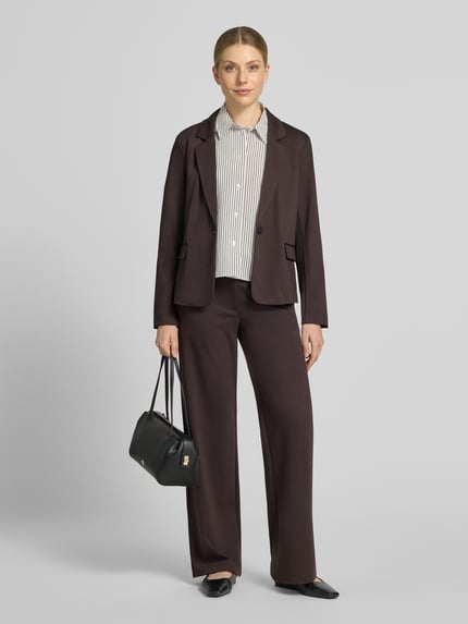 Frauenmodel trägt Regular Fit Blazer mit Viskose-Anteil Modell 'Nanni' von FREE/QUENT, Dunkelbraun, Klappentaschen, Revers, Ganzkörperansicht von vorne. Elastischer Material-Mix, Knopfverschluss, gestreifte Bluse, schwarze Tasche und Hose sichtbar.